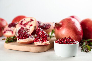 Delicious ripe pomegranates on white wooden table