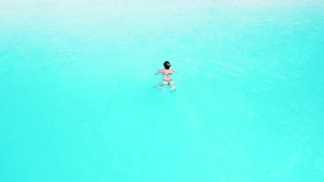 Aerial view of woman swimming in beautiful turquoise water, summer vacations concept.