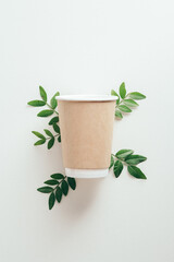 Eco-friendly disposable coffee cup with green leaves on white background, Zero waste, plastic free, sustainable lifestyle concept.