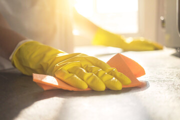 Woman cleaning the counter table top in home kitchen with a spray detergent