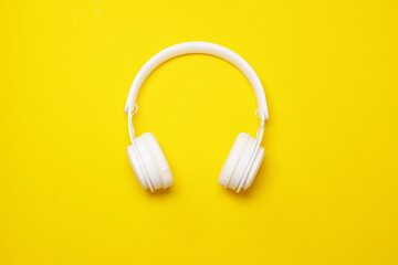 Modern white wireless headphones on a yellow background, Trendy minimal style.