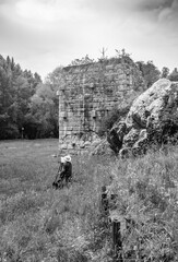 An artist paints live the ruins of the Roman arch bridge of Augustus, in Narni, Terni, Umbria. Plein air painting, impressionism. The remains of the bridge over the Nera river, surrounded by nature.