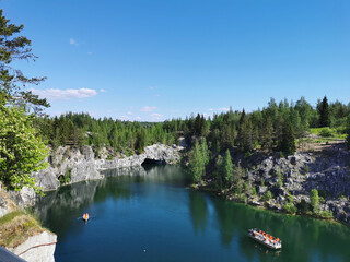 View from the observation deck of the turquoise water of the Marble Canyon in the Ruskeala Mountain Park with the reflection of the sky and trees on a sunny summer day.