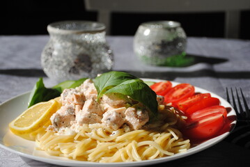 Italian cuisine: spaghetti with salmon, cream cheese and basil and tomatoes close-up on plate