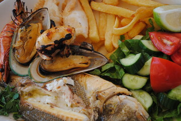 Seafood platter. Roasted shrimps, fish and Mussels with potato chips, tomatoes, cucumbers, herbs and lemon