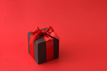 Black gift box with red bow on red background