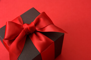 Black gift box with red bow on red background