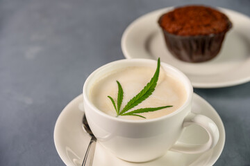 Hot Coffee drink with cannabis leaf on top of foam and cake or muffin