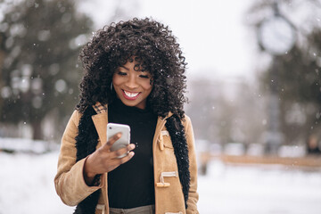 Afro american woman with phone in winter
