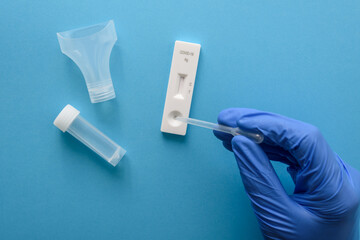 Hand in protective glove making antigen covid test with pipette and saliva - obrazy, fototapety, plakaty