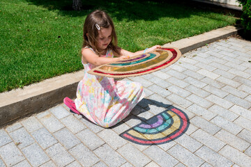 Cute child girl in tie dye dress playing with rainbow suncatcher outside. Fun crafting ideas for...