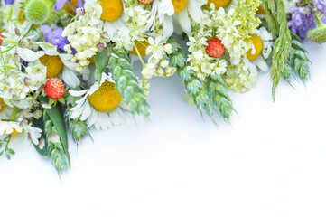 On a white background with space for writing text, blurred image of a part of a bouquet of daisies, spikelets and wildflowers.Floral background.