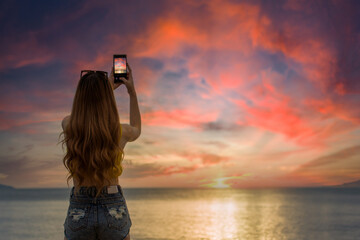 Fototapeta premium woman shootting photo on the beach at sunset