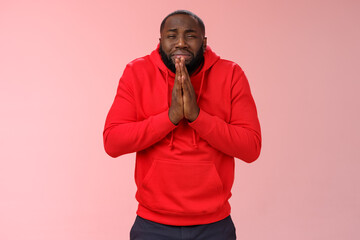 Miserable african american man beard in red hoodie stooping make supplicating upset grimace grying sobbing asking help say please hold hands pray begging mercy, apologizing need money