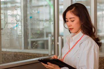 Fototapeta na wymiar Woman scientist typing on tablet in laboratory