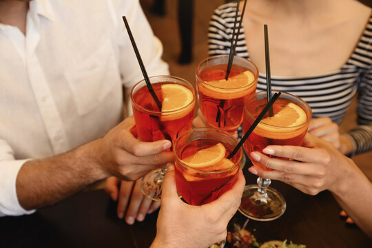 Friends with Aperol spritz cocktails resting together at restaurant, closeup