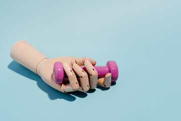 Wooden hand with a pink dumbbell on blue background. Sport and exercise. 3d illustration