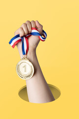 Hand of woman holding gold medal on yellow background.award and victory concept.copy space