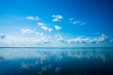 White fluffy clouds blue sky above a surface of the sea. Beautiful sky and ocean using for...