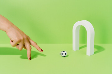 Hand of an unknown woman playing with a soccer ball on a goal on a green background. football and sport concept.