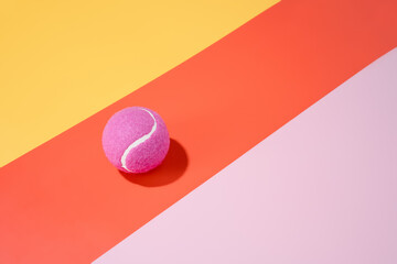 a pink tennis ball on a yellow, orange and pink background.sport.abstract.3d illustration
