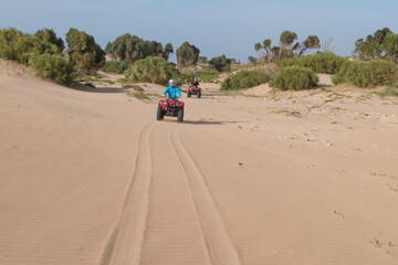 Beautiful sunny day at Essaouira, Morocco with two quad bike drivers riding on the sand © Maximilian Obermaier/Wirestock