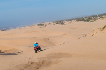 Beautiful sunny day at the beach in Essaouira, Morocco with a man driving a quad bike on the sand