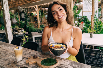Smiling ethnic woman with breakfast bowl in hands