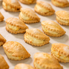 Hot open buns with cottage cheese on baking paper. Top side view. Soft focus.