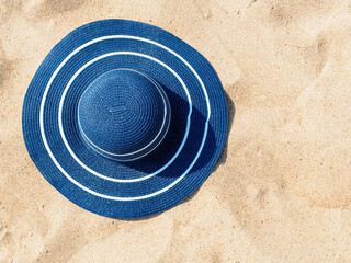 large blue straw hat on the sand, copy space. Beach holiday concept