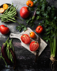 Fresh harvest of vegetables and herbs. Farm production of vegan food. Tomatoes, eggplant, string beans and celery on a dark background.