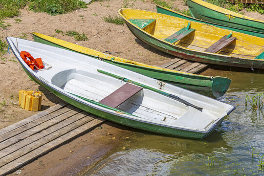 Empty shabby plastic boat for river walks stands on the shore of the pond