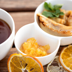 Orange jam with simple pancakes or crepes and cup of tea on rustic table. Delicious American breakfast or dessert. Soft focus.