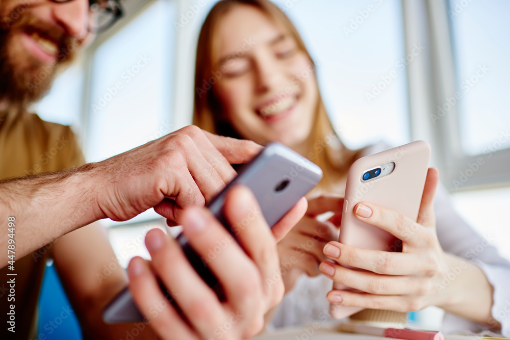 Poster blurred male and female bloggers checking mobile notification during friendly meeting for online net