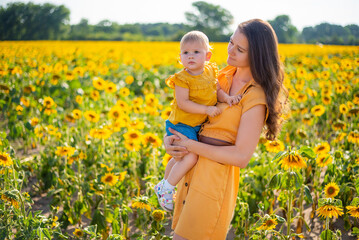 Happy mother and her little daughter in the sunflower field