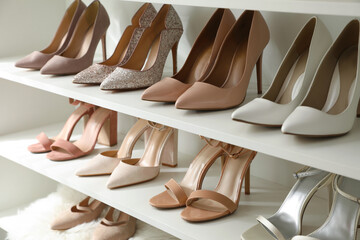 Different stylish women's shoes on shelving unit - obrazy, fototapety, plakaty