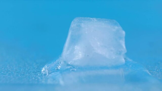 Melting ice cube isolated on blue background.