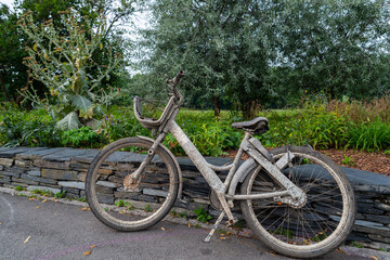 Fototapeta premium an abandoned bike totally dirty and rusted on a small wall in a park