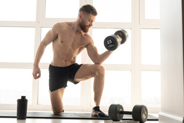 Plakat Sportsman do exercise with dumbbell on fitness mat