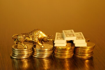 Metal bull with coins close-up on the table. Next to the bundles of dollars. Business concept.