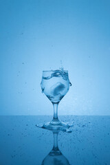 Splash of water in the glass. Reflective table.