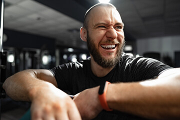 Fototapeta na wymiar Cheerful smiling man bodybuilder standing in a gym