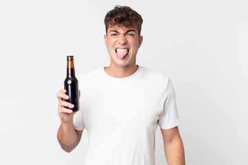 young handsome man feeling disgusted and irritated and tongue out and holding a beer bottle