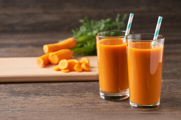 Fresh carrot juice in glasses on a  rustic wooden table, selective focus.