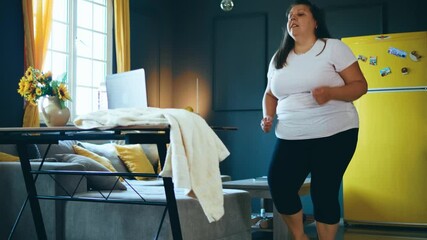Plus size woman  doing workout with squats online watching video tutorial on laptop at home. 