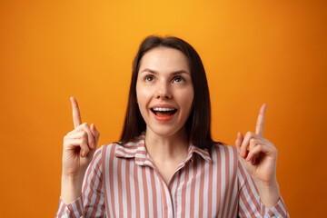 Young positive woman points fingers at copy space