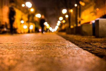 Alley in the night city, the people go on the road lit lanterns. Close up view from the sidewalk level