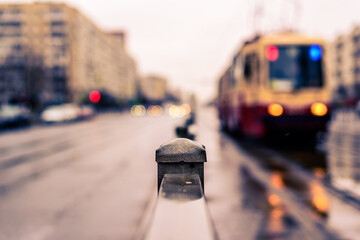 Rainy day in the big city, the headlights of the approaching tram. Close up view, from the handrail...