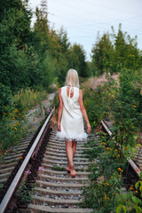 Adult woman on nature in summer forest on railway of dusk