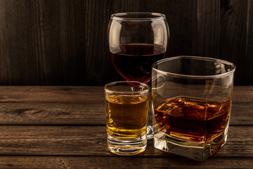 Three glasses with brandy, tequila and red wine on an old wooden table. Angle view